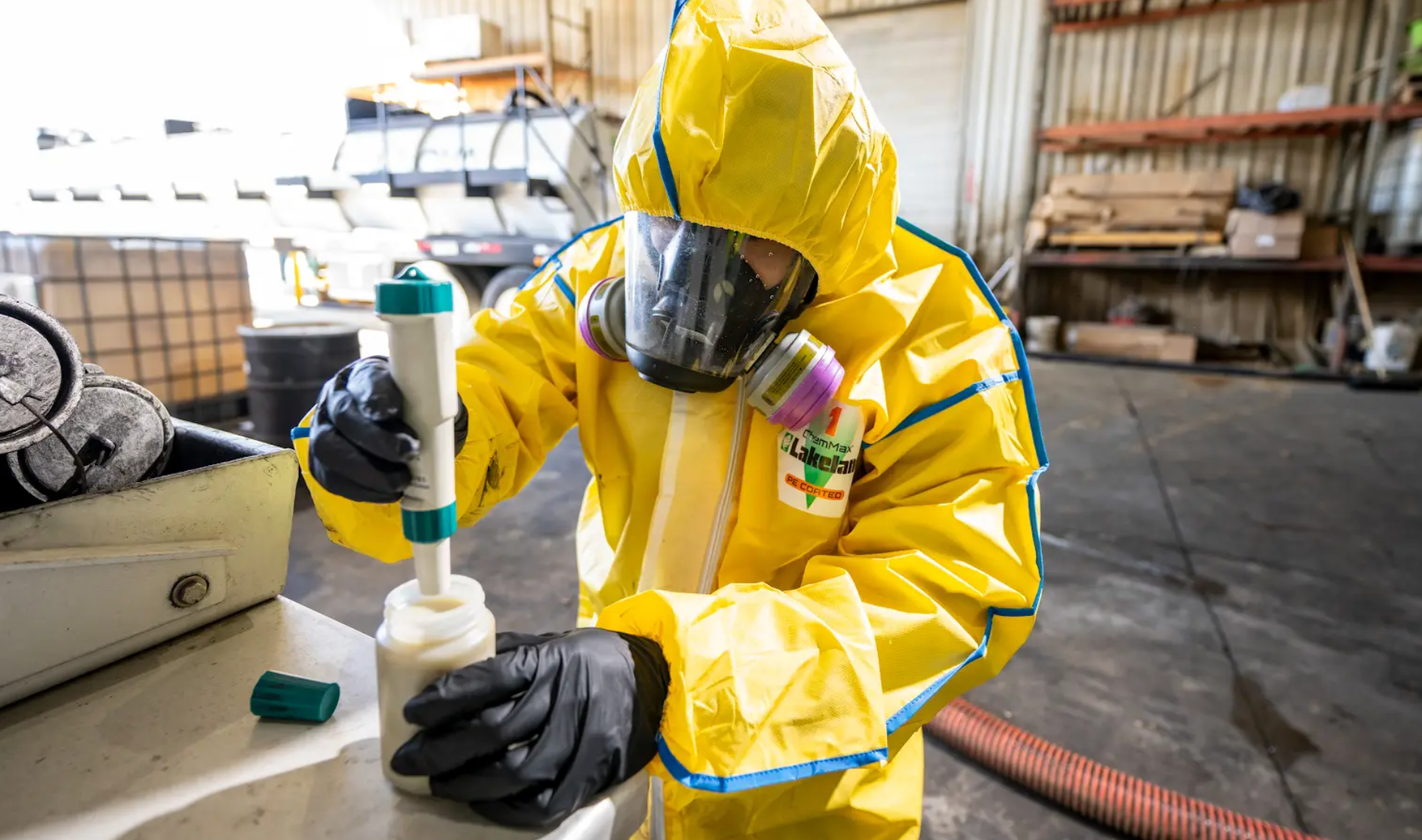 Worker in hazmat suit testing a bottle of chemicals